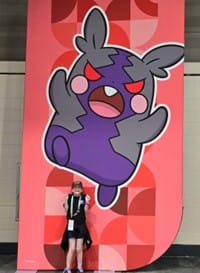 girl laughing in front of a pokemon poster